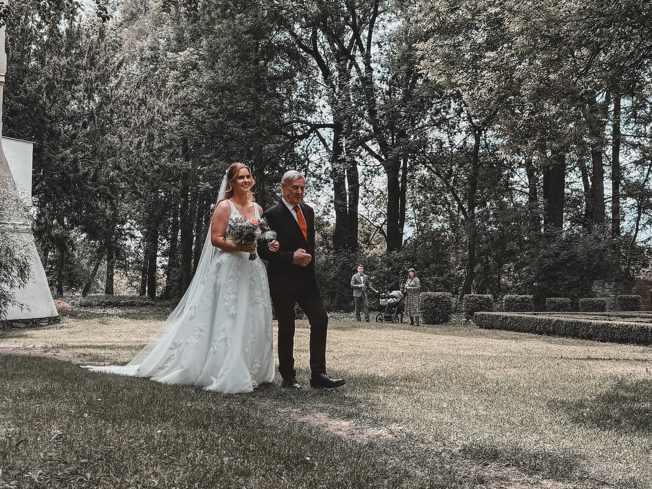 Nádherná nevěsta přichází k oltáři v doprovodu tatínka na Chateau Třebešice